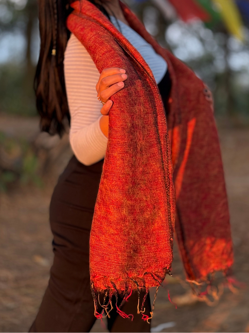 Woman wearing a red scarf outdoors with blurred colorful flags in the background